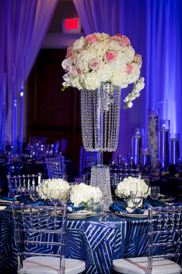 tall crystal centerpieces on a luxurious navy blue and silver tablecloth with acrylic Chiavari chairs