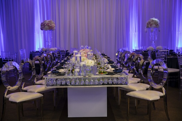 Navy blue, blush and silver wedding decor with long mirrored dining tables and light blue uplighting