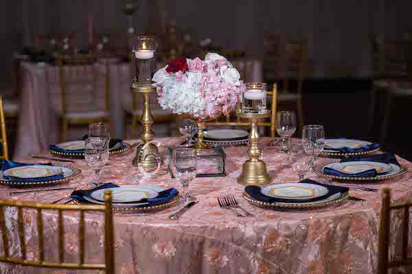 pink and gold wedding reception table with navy blue napkins and custom menu cards
