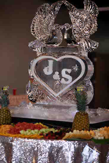 monogrammed ice carving of two doves surrounded by a fruit and cheese display