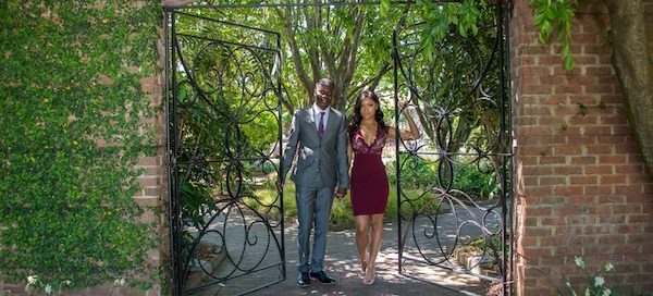 bride and groom to be posing for engagement photos inext to a wrought iron gate