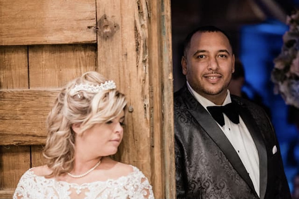 bride and groom on opposite sides of a rustic wooden door